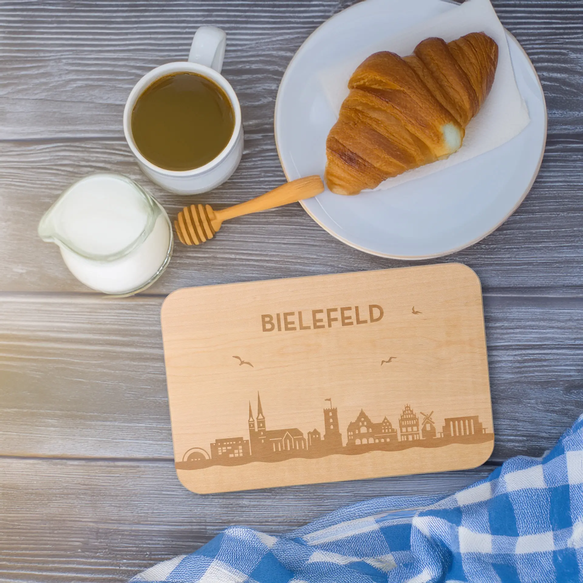 Croissant, Milch, Milchkännchen, Becher, Untersetzer mit Stadtmotiv